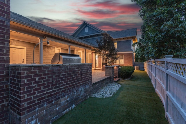 458 Wiregrass Ln, Franklin, TN 37064 - property exterior at dusk featuring brick siding, an outdoor kitchen, roof with shingles, and a patio
