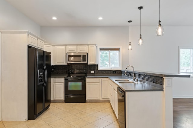 kitchen with black appliances, a sink, dark countertops, a peninsula, and backsplash