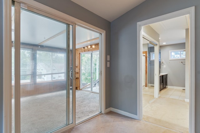 entryway featuring light colored carpet, healthy amount of natural light, and baseboards