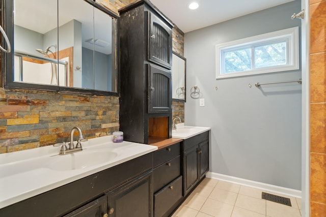 bathroom with decorative backsplash, tile patterned floors, double vanity, and baseboards