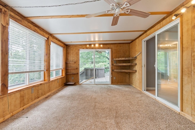 unfurnished living room featuring wooden walls, carpet floors, and a ceiling fan
