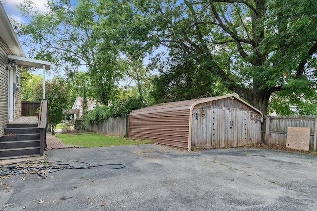 view of patio / terrace featuring a storage shed, fence, an outbuilding, and a wooden deck