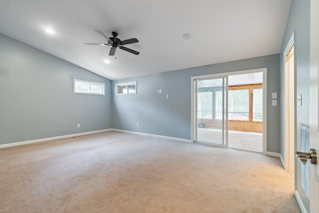 empty room with light colored carpet, lofted ceiling, a ceiling fan, healthy amount of natural light, and baseboards