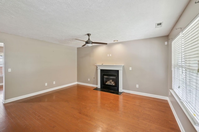325 Golfview Ln, Springfield, TN 37172 - unfurnished living room featuring ceiling fan, plenty of natural light, wood finished floors, a fireplace with flush hearth, and a textured ceiling