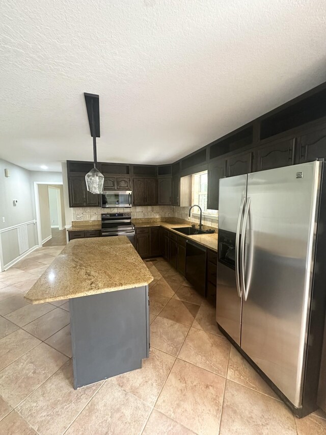 6900 Snow View Ln, Ooltewah, TN 37363 - kitchen featuring appliances with stainless steel finishes, a sink, backsplash, a center island, and light stone counters