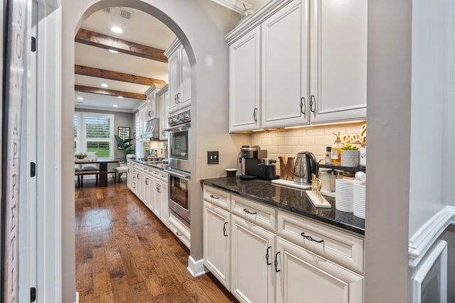 810 Pine Terrace Dr, Brentwood, TN 37027 - kitchen featuring arched walkways, dark wood-style flooring, tasteful backsplash, beamed ceiling, and dark stone countertops