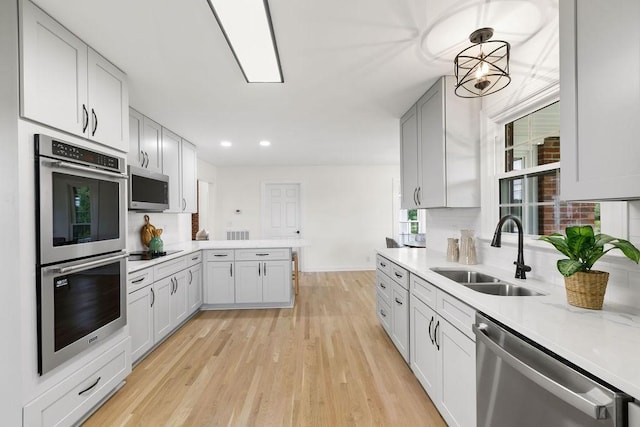 754 Veterans Pkwy, Murfreesboro, TN 37128 - kitchen with a sink, appliances with stainless steel finishes, light countertops, light wood-style floors, and a peninsula