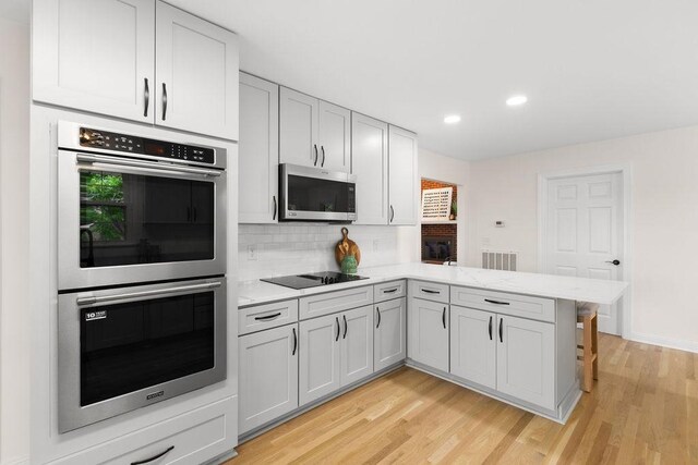 754 Veterans Pkwy, Murfreesboro, TN 37128 - kitchen featuring appliances with stainless steel finishes, a peninsula, light wood finished floors, decorative backsplash, and recessed lighting