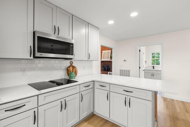 754 Veterans Pkwy, Murfreesboro, TN 37128 - kitchen with stainless steel microwave, black electric cooktop, a peninsula, decorative backsplash, and recessed lighting