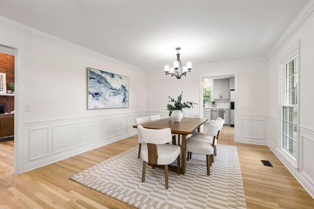 754 Veterans Pkwy, Murfreesboro, TN 37128 - dining room with a chandelier, light wood-style floors, a decorative wall, ornamental molding, and a wainscoted wall