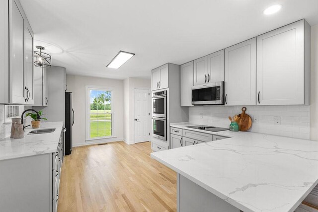 754 Veterans Pkwy, Murfreesboro, TN 37128 - kitchen with appliances with stainless steel finishes, a sink, light stone counters, light wood-style flooring, and backsplash