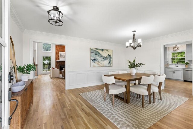 754 Veterans Pkwy, Murfreesboro, TN 37128 - dining area with a chandelier, light wood-style floors, crown molding, a fireplace, and wainscoting