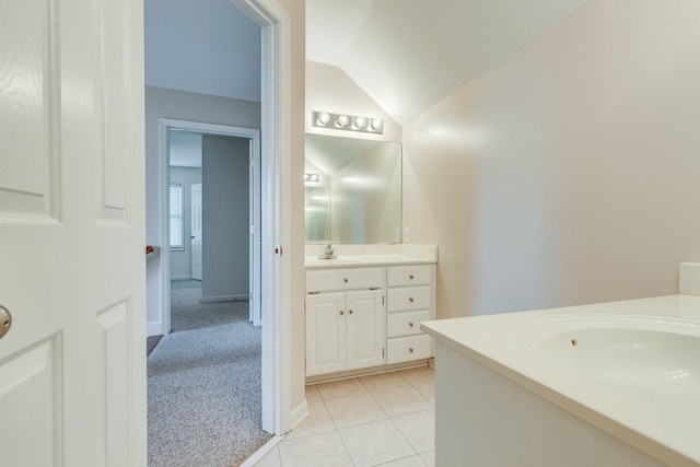 bathroom featuring two vanities, lofted ceiling, tile patterned floors, and baseboards