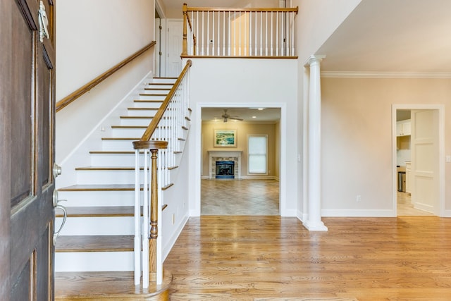 staircase with crown molding, ceiling fan, decorative columns, wood finished floors, and baseboards