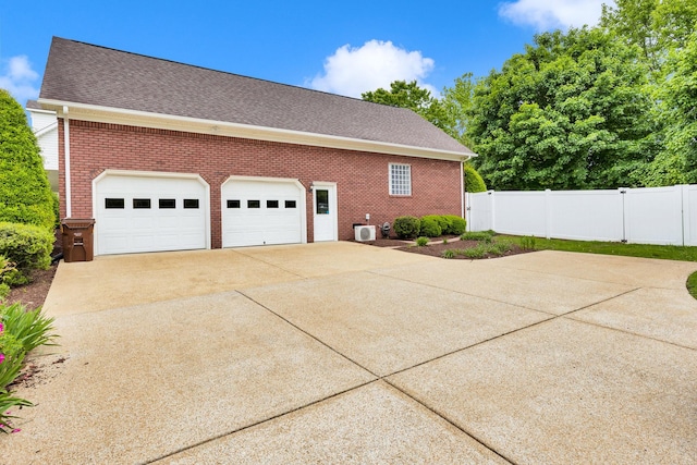 view of home's exterior with brick siding, driveway, fence, roof with shingles, and an attached garage