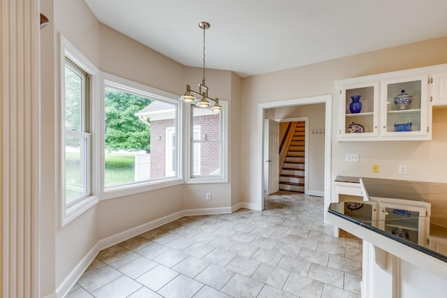 unfurnished dining area with healthy amount of natural light, stairs, and baseboards