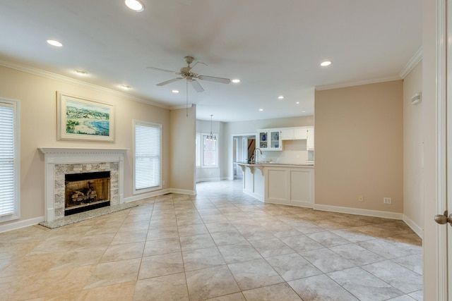 unfurnished living room featuring ceiling fan, a fireplace, ornamental molding, a sink, and recessed lighting