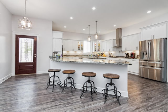 kitchen featuring stainless steel appliances, wall chimney range hood, tasteful backsplash, glass insert cabinets, and recessed lighting