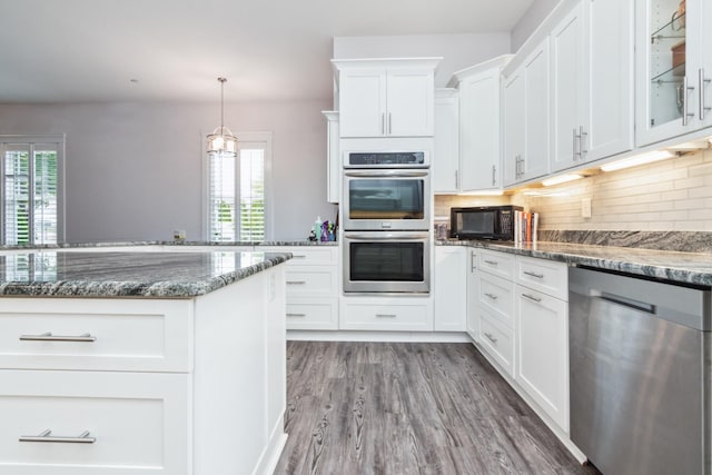 kitchen featuring appliances with stainless steel finishes, plenty of natural light, decorative backsplash, and dark stone counters