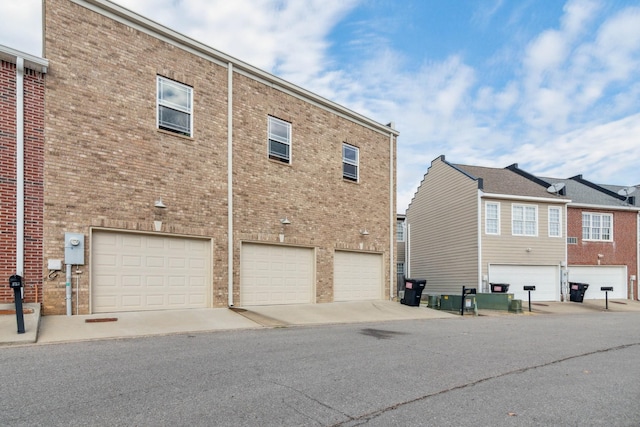 rear view of property featuring an attached garage and brick siding