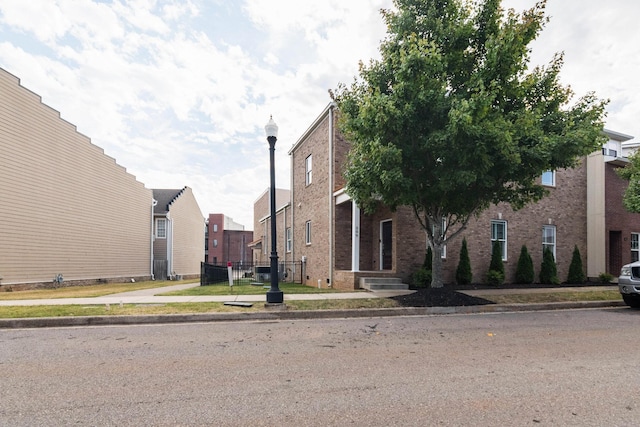 view of property exterior featuring brick siding, a residential view, and fence