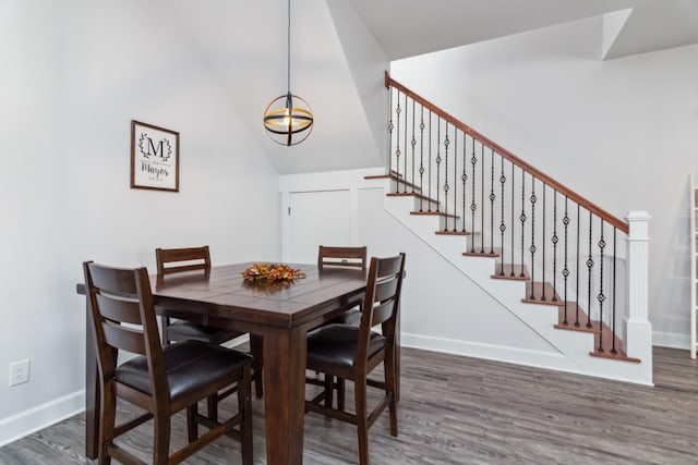 dining room featuring wood finished floors, stairway, baseboards, and lofted ceiling
