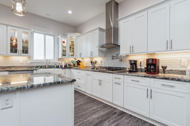 kitchen with wall chimney exhaust hood, a sink, appliances with stainless steel finishes, white cabinets, and glass insert cabinets
