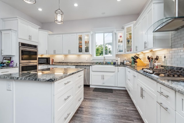 kitchen featuring stainless steel appliances, wall chimney range hood, a sink, recessed lighting, and white cabinets