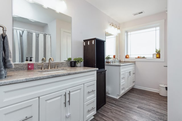 full bathroom featuring two vanities, wood finished floors, and baseboards