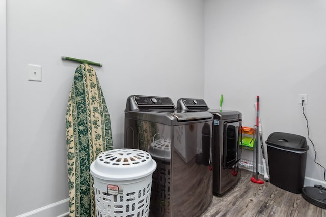 clothes washing area featuring separate washer and dryer, wood finished floors, and baseboards