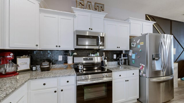 kitchen featuring stainless steel appliances, white cabinets, and tasteful backsplash