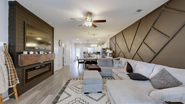 living room with light wood-style flooring, ceiling fan, and a chandelier