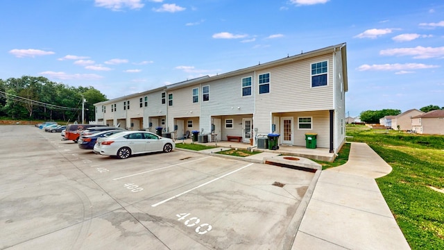 view of front of home with uncovered parking, central air condition unit, and a front lawn