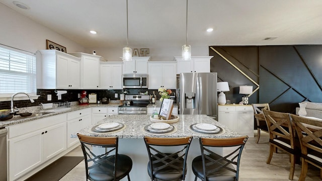 kitchen featuring appliances with stainless steel finishes, a sink, white cabinetry, decorative backsplash, and recessed lighting