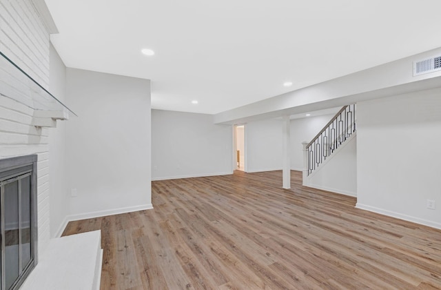 unfurnished living room with wood finished floors, stairs, a fireplace, baseboards, and recessed lighting