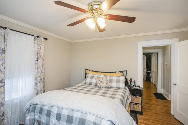 bedroom featuring crown molding, wood finished floors, and a ceiling fan
