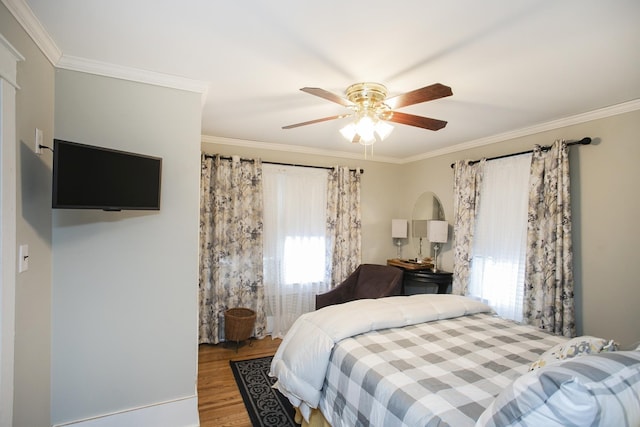 bedroom with multiple windows, crown molding, wood finished floors, and ceiling fan