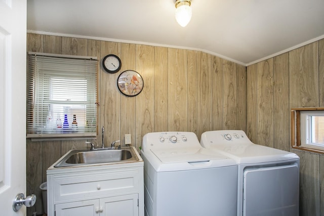 clothes washing area featuring independent washer and dryer, a sink, and wooden walls