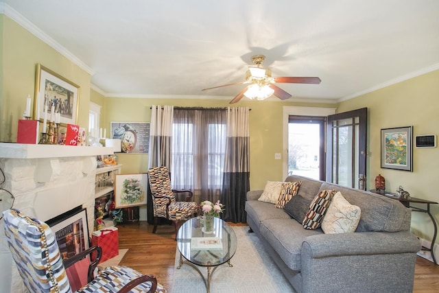 living area featuring wood finished floors, ceiling fan, a fireplace with flush hearth, and crown molding