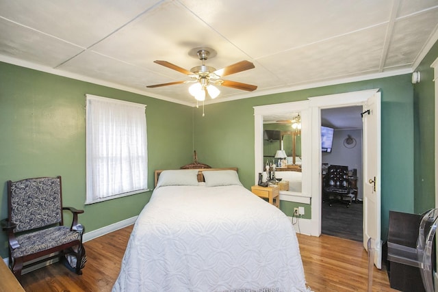 bedroom with ornamental molding, wood finished floors, baseboards, and ceiling fan