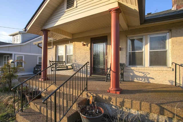 entrance to property with brick siding and a porch