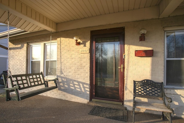 property entrance with a porch and brick siding