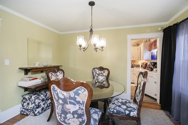 dining area featuring dark wood-style floors, a chandelier, ornamental molding, and baseboards