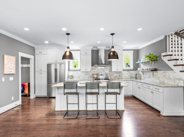 3610 Pilcher Ave, Nashville, TN 37209 - kitchen featuring wall chimney exhaust hood, high end fridge, crown molding, range, and white cabinetry