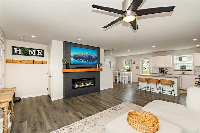 living room featuring a fireplace, recessed lighting, dark wood-style flooring, baseboards, and ceiling fan