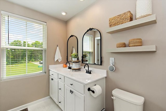 bathroom featuring toilet, baseboards, and double vanity