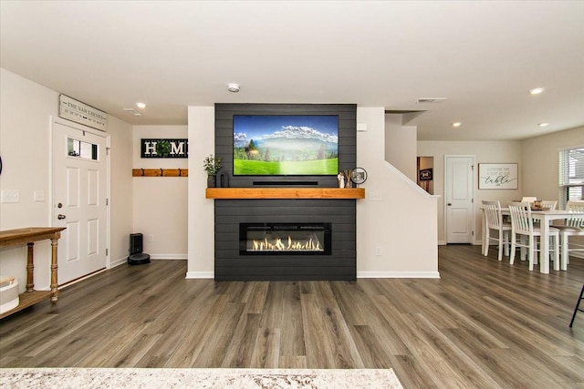 living room with wood finished floors, recessed lighting, a large fireplace, and baseboards