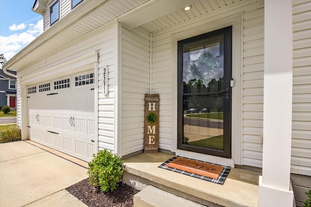 doorway to property featuring an attached garage and driveway