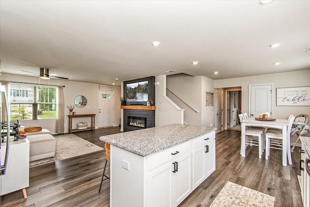 kitchen featuring a glass covered fireplace, white cabinets, a kitchen island, open floor plan, and recessed lighting