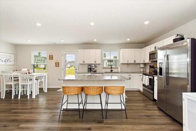 kitchen featuring appliances with stainless steel finishes, a kitchen island, a breakfast bar area, recessed lighting, and white cabinetry